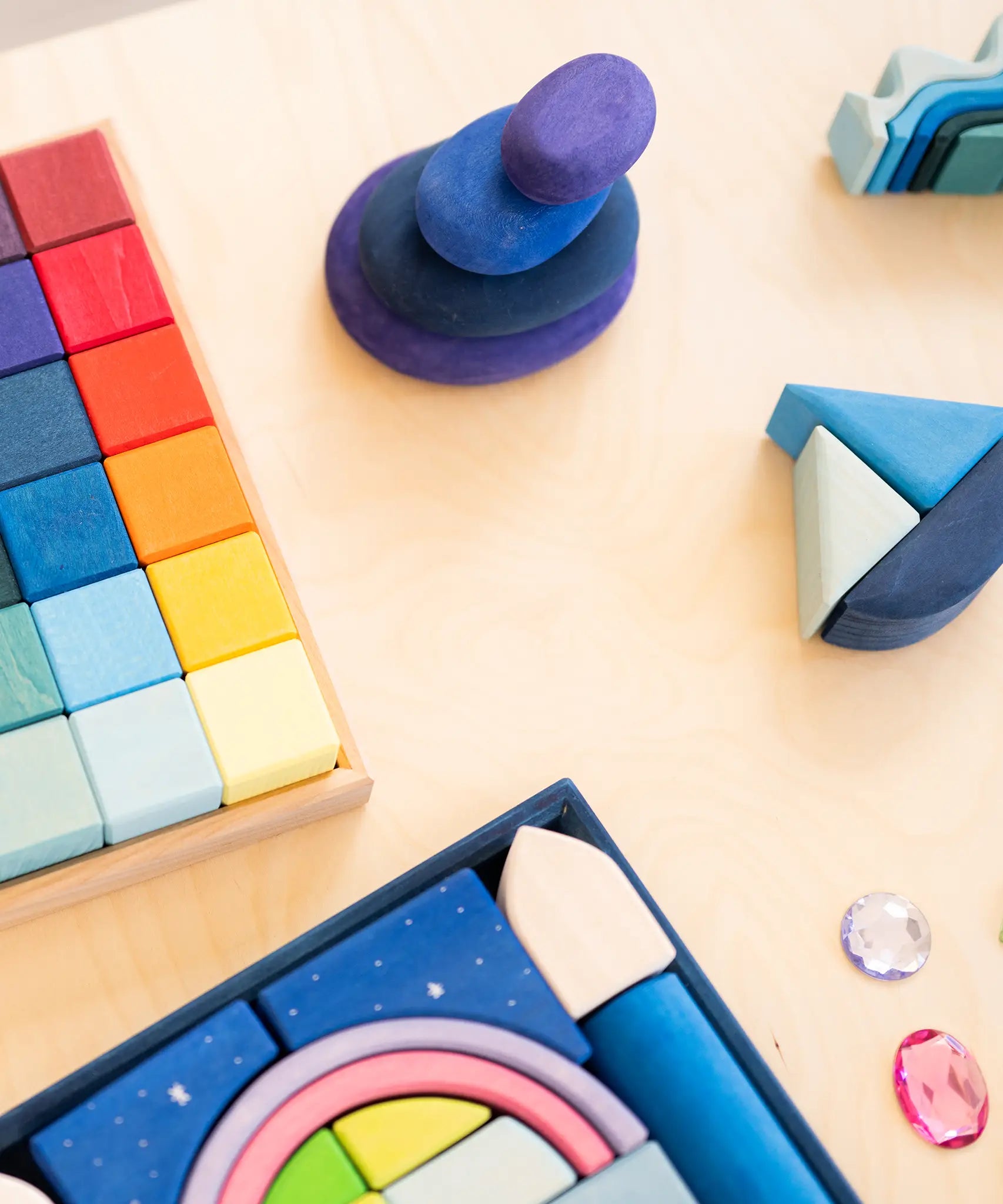 Grimms limited edition dream pebbles on a table next to rainbow cubes and a polar light set.