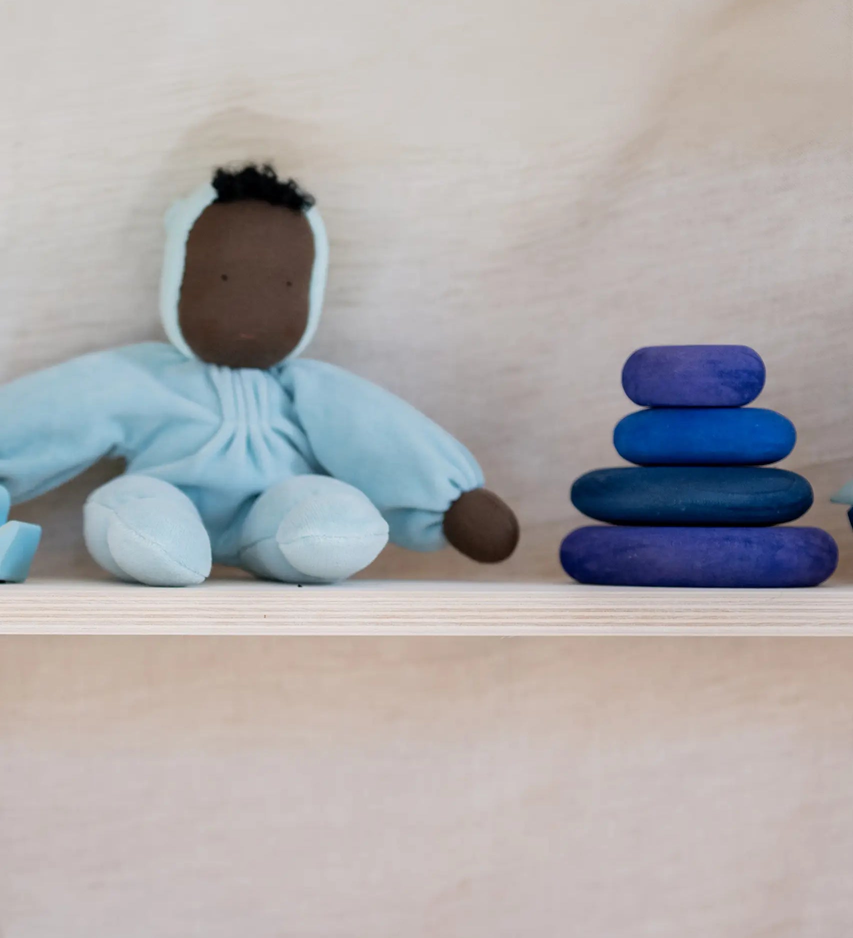 Grimm's dream limited edition handcrafted wooden pebbles displayed on a shelf next to a waldorf doll