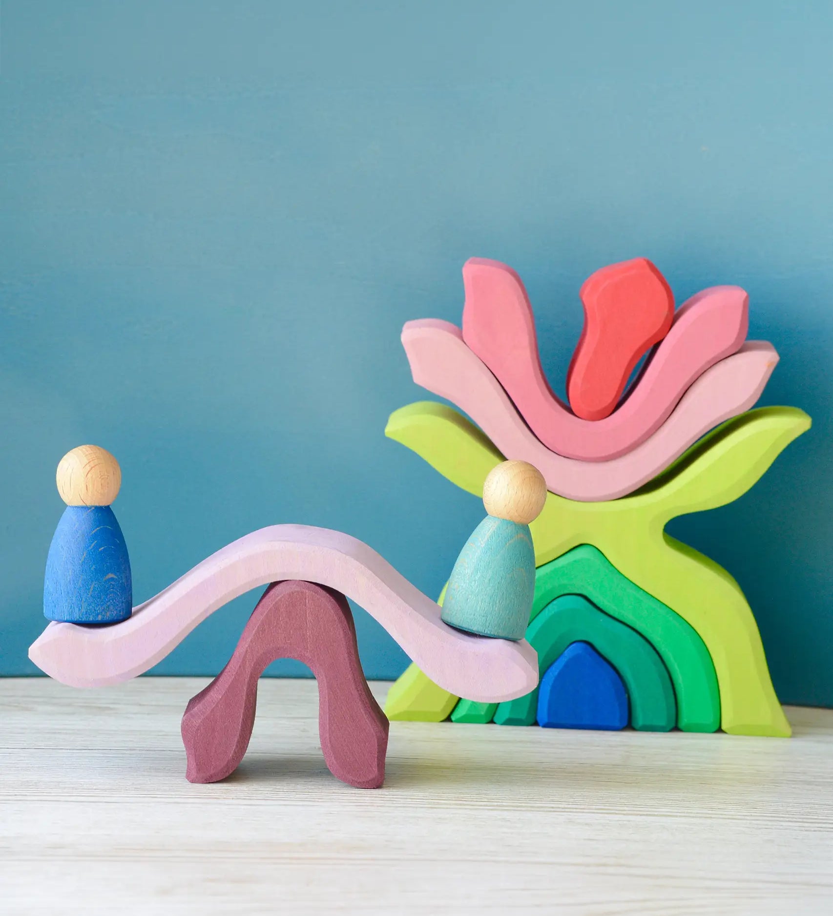 Pieces from the Grimms wooden little flower set made into a see saw with peg dolls sitting on top