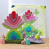 Grimm's little flower wooden stacking toy on display next to friends wooden peg dolls. 
