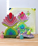 Grimm's little flower wooden stacking toy on display next to friends wooden peg dolls. 