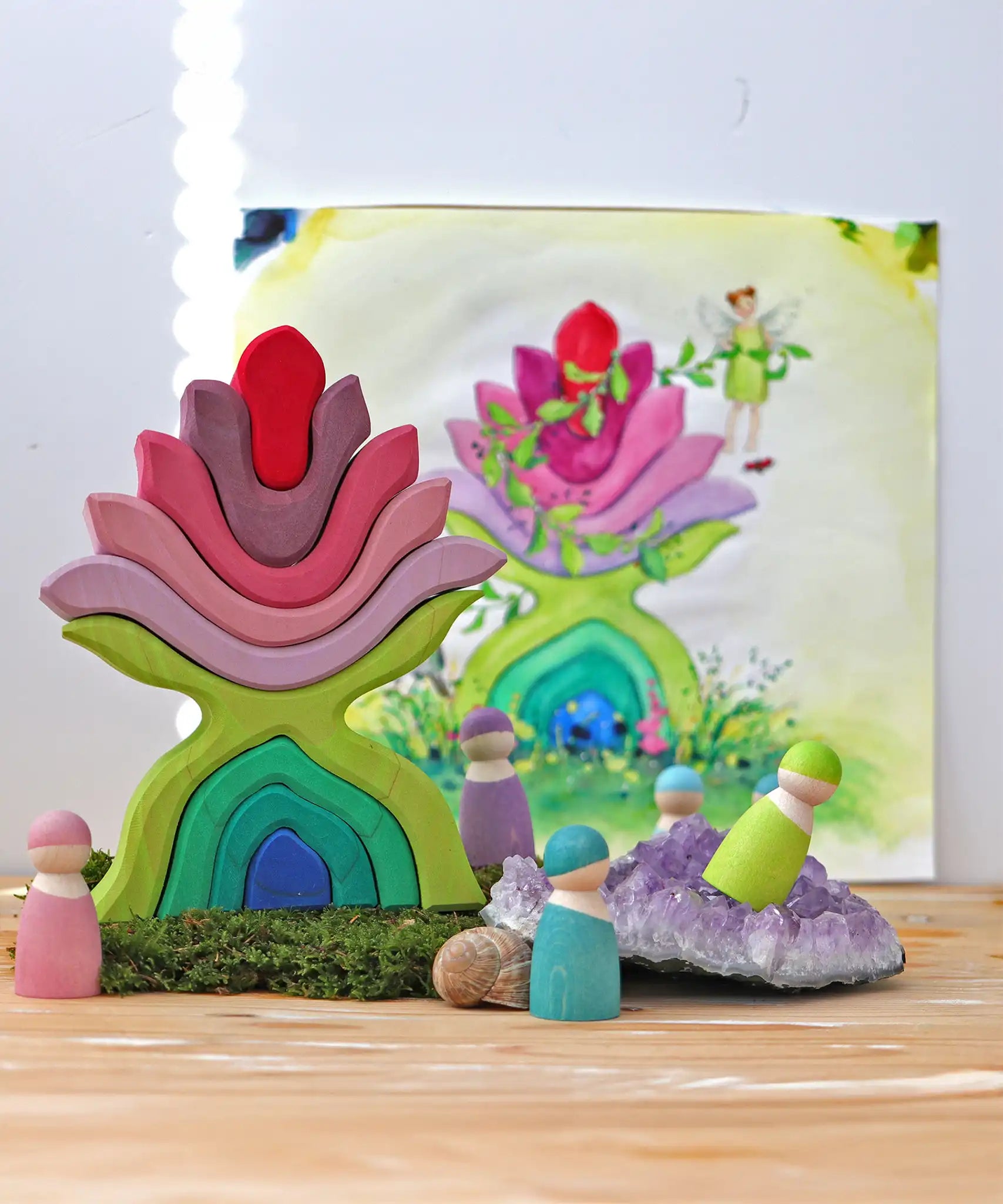 Grimm's little flower wooden stacking toy on display next to friends wooden peg dolls. 