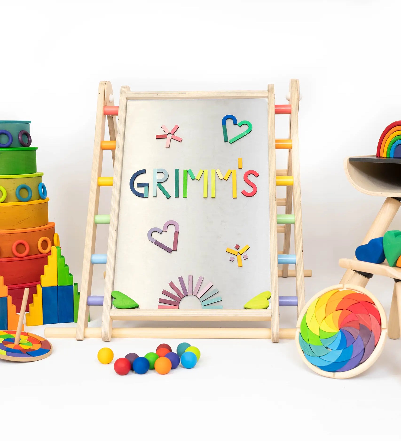 Pieces from the Grimms magnet alphabet puzzle on a Triclimb Biri board next to other popular rainbow block and buildings sets