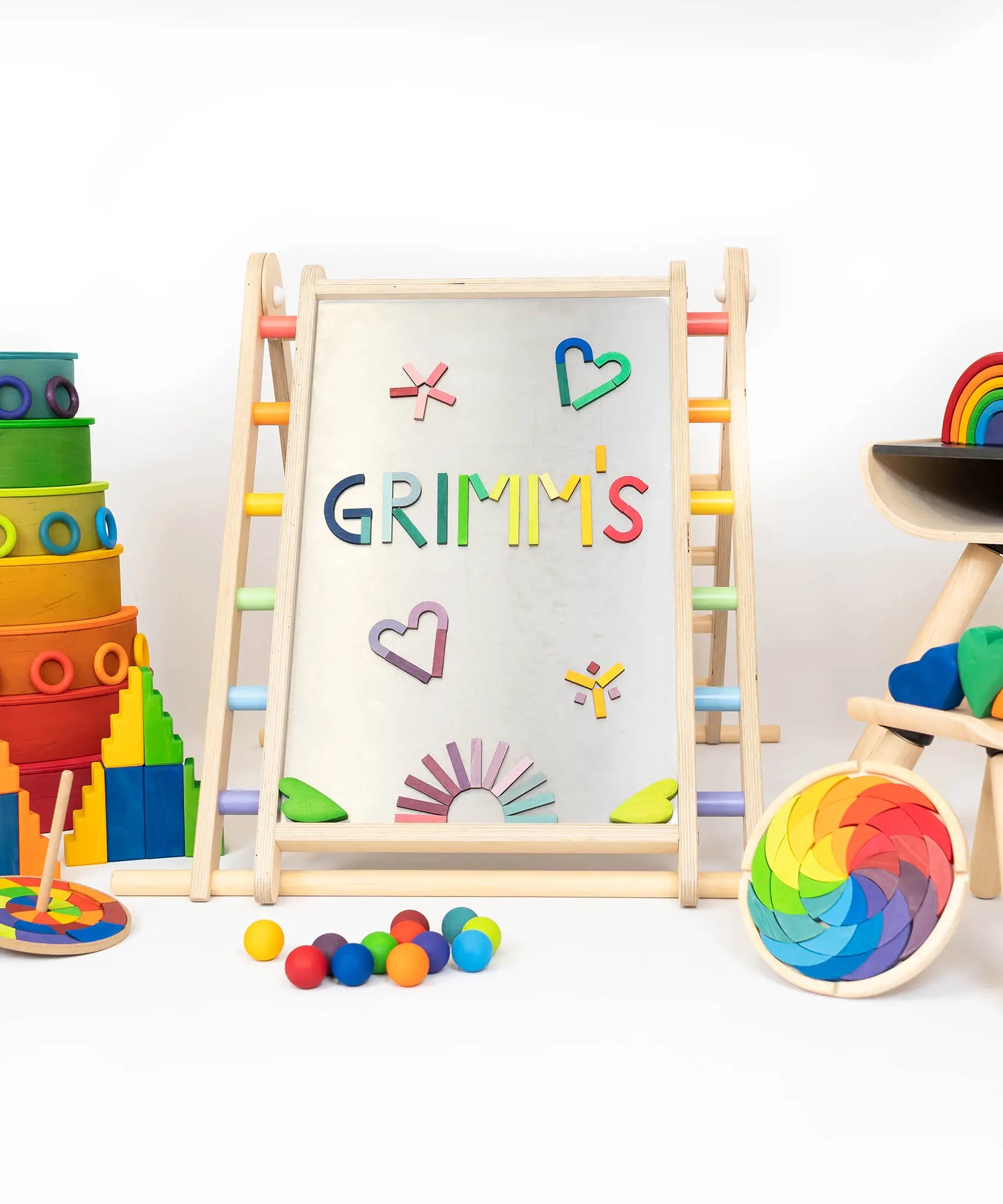 Pieces from the Grimms magnet alphabet puzzle on a Triclimb Biri board next to other popular rainbow block and buildings sets