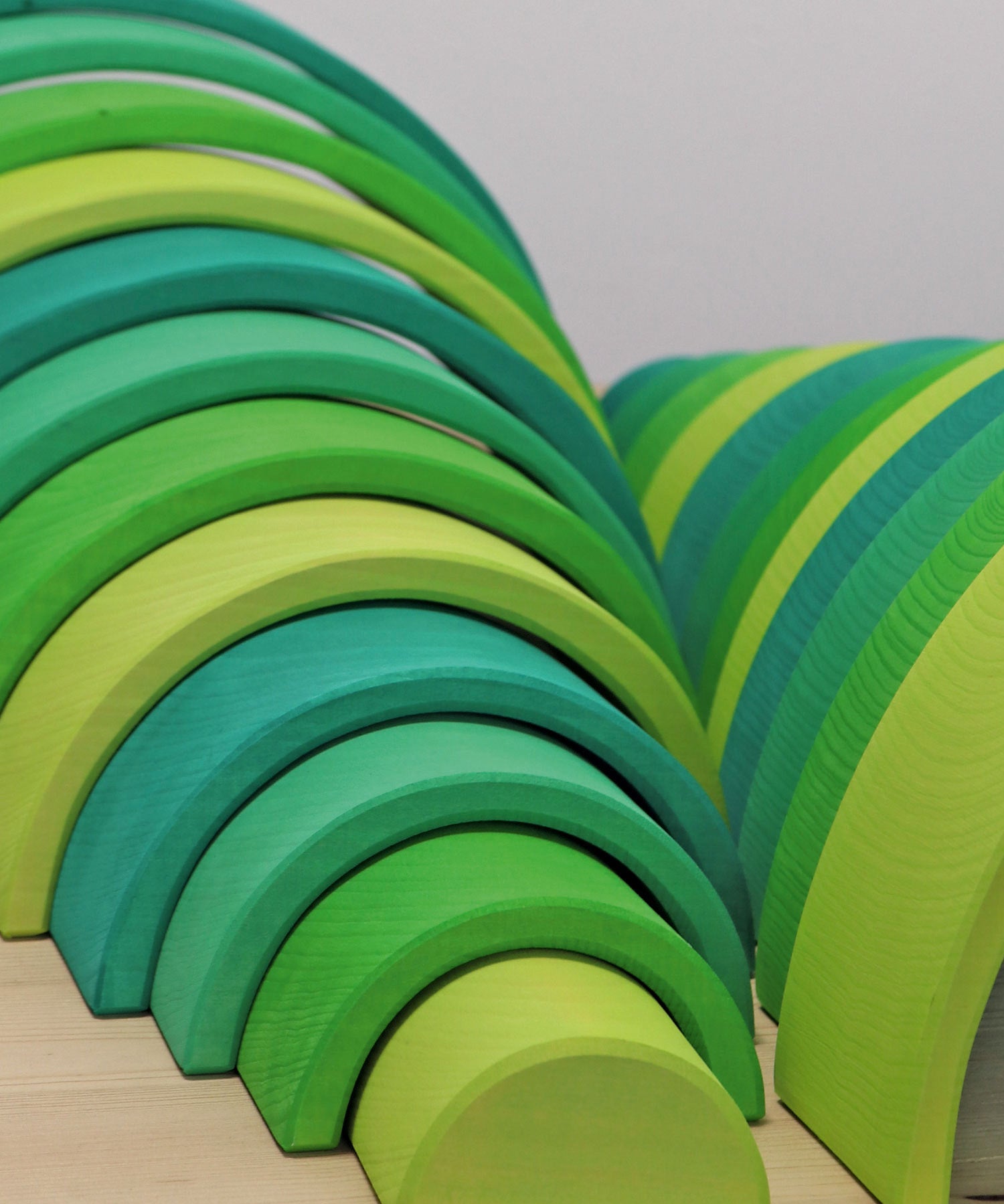 A close up of the Grimms meadow large green wooden rainbow set available at Babipur showing the grain detail