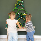 2 children making a Christmas tree stack using pieces from the meadow and forest Grimms rainbow pieces. Both of these sets are available at Babipur.