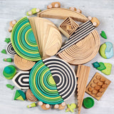 A circular flatlay made from different Grimms sets and pieces including the meadow and forest wooden rainbow 12 piece 