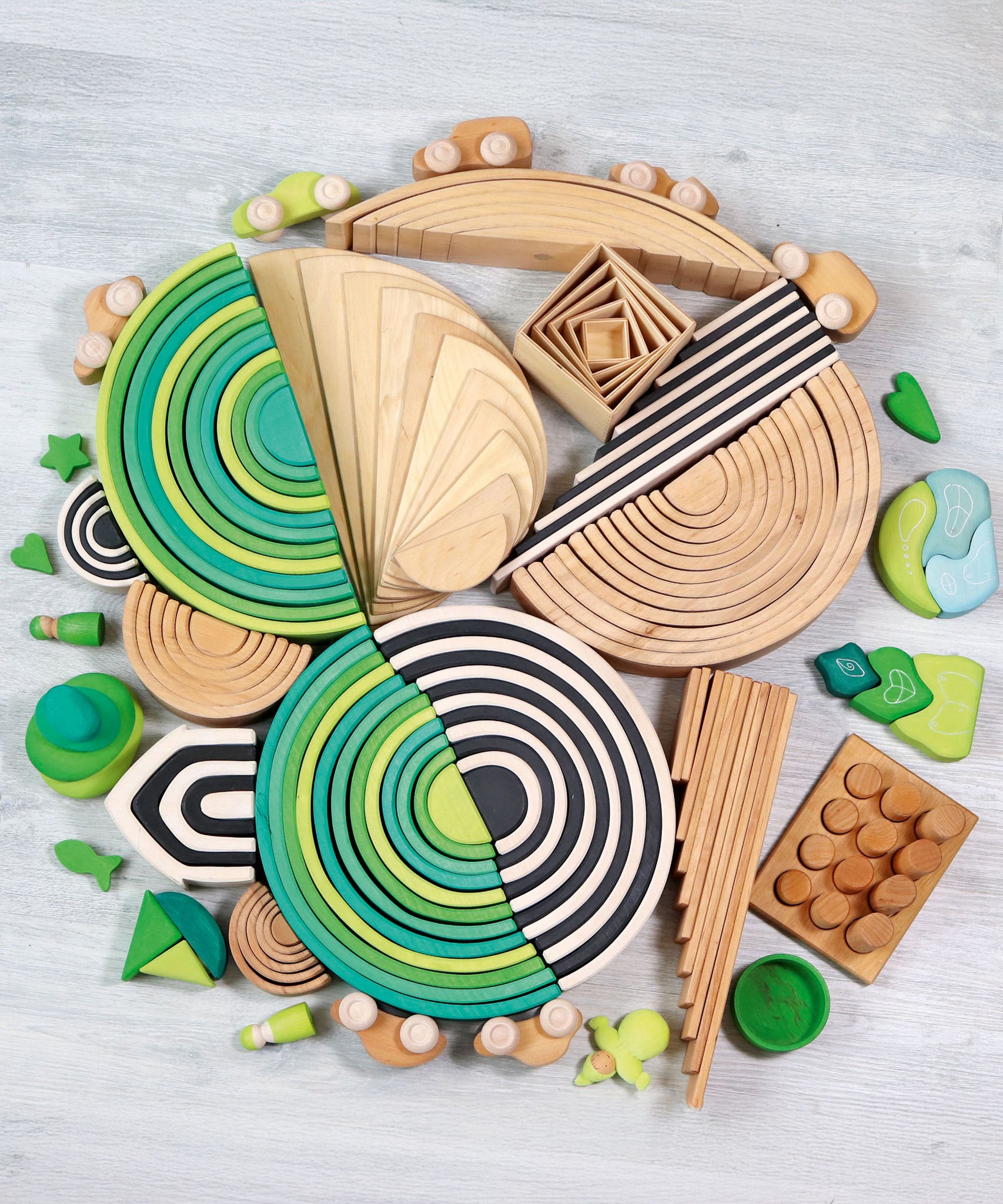 A circular flatlay made from different Grimms sets and pieces including the meadow and forest wooden rainbow 12 piece 