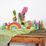 A Grimm's Medium Pastel Rainbow (6 Pieces) on a sideboard with other wooden Grimm's items including wooden balls, forest, mushrooms and gnomes. 