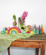 A Grimm's Medium Pastel Rainbow (6 Pieces) on a sideboard with other wooden Grimm's items including wooden balls, forest, mushrooms and gnomes. 