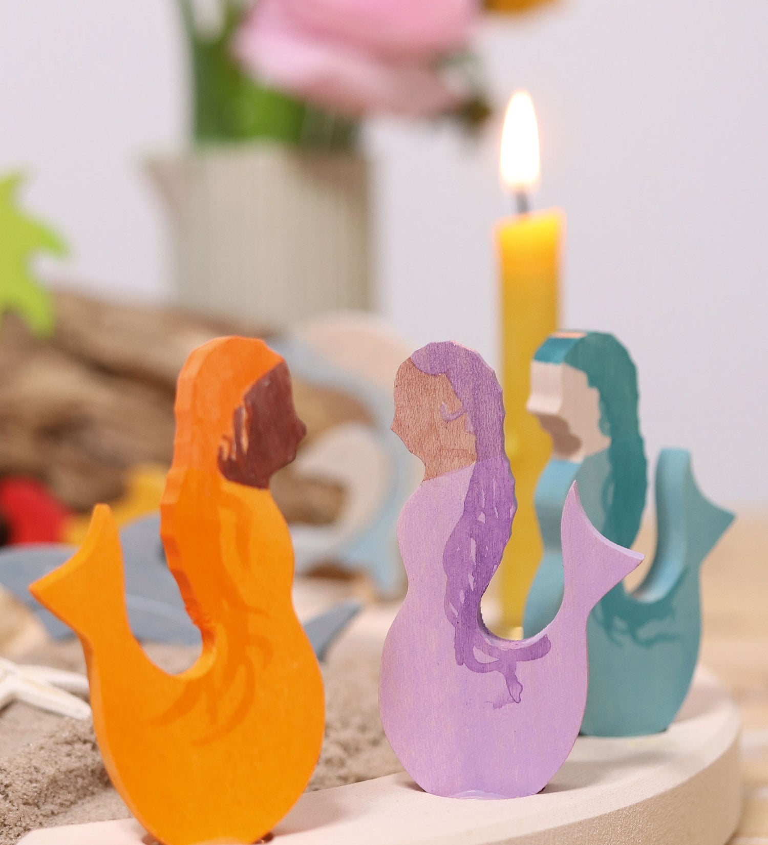 A close up of the purple, blue and orange mermaid wooden Grimms decorative figures slotted in the celebration ring showing the hand painted detail