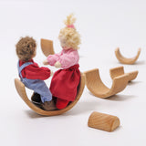 2 Grimms dolls sitting inside one of the arches from the Grimms natural wooden rainbow stacking toy available at Babipur. 