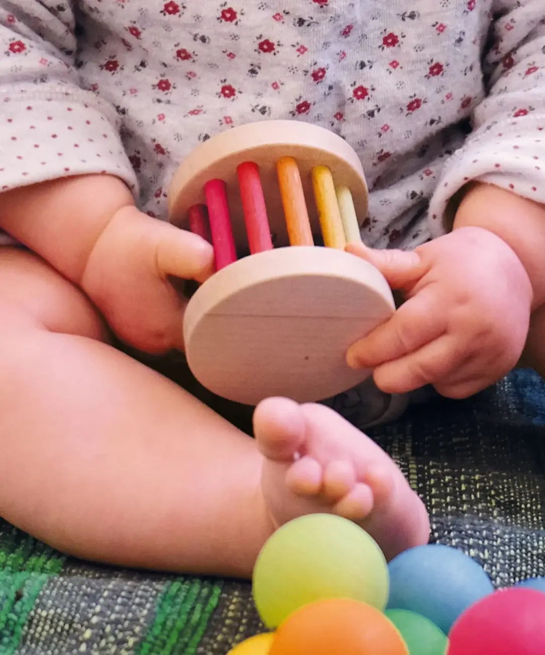 Baby holding a Grimms wooden mini rolling wheel