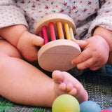 Baby holding a Grimms wooden mini rolling wheel