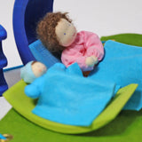 Pieces from the Grimm's blue and green mobile dolls home wooden toy play set used as bed and a crib.