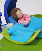 Pieces from the Grimm's blue and green mobile dolls home wooden toy play set used as bed and a crib.