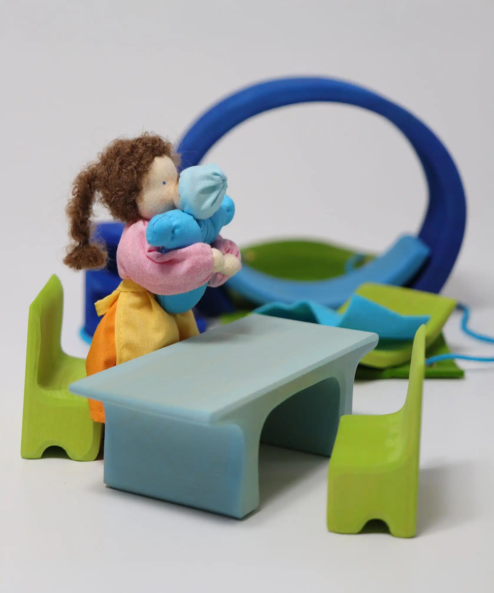 Grimm's blue and green mobile dolls home wooden toy play set table and chairs with Grimm's dolls placed besides it.