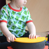 Child building a stack using Grimms monochrome arch and rainbow semi circle pieces