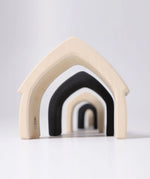 Loose Grimms handcrafted wooden monochrome house pieces lined up from large to small. 