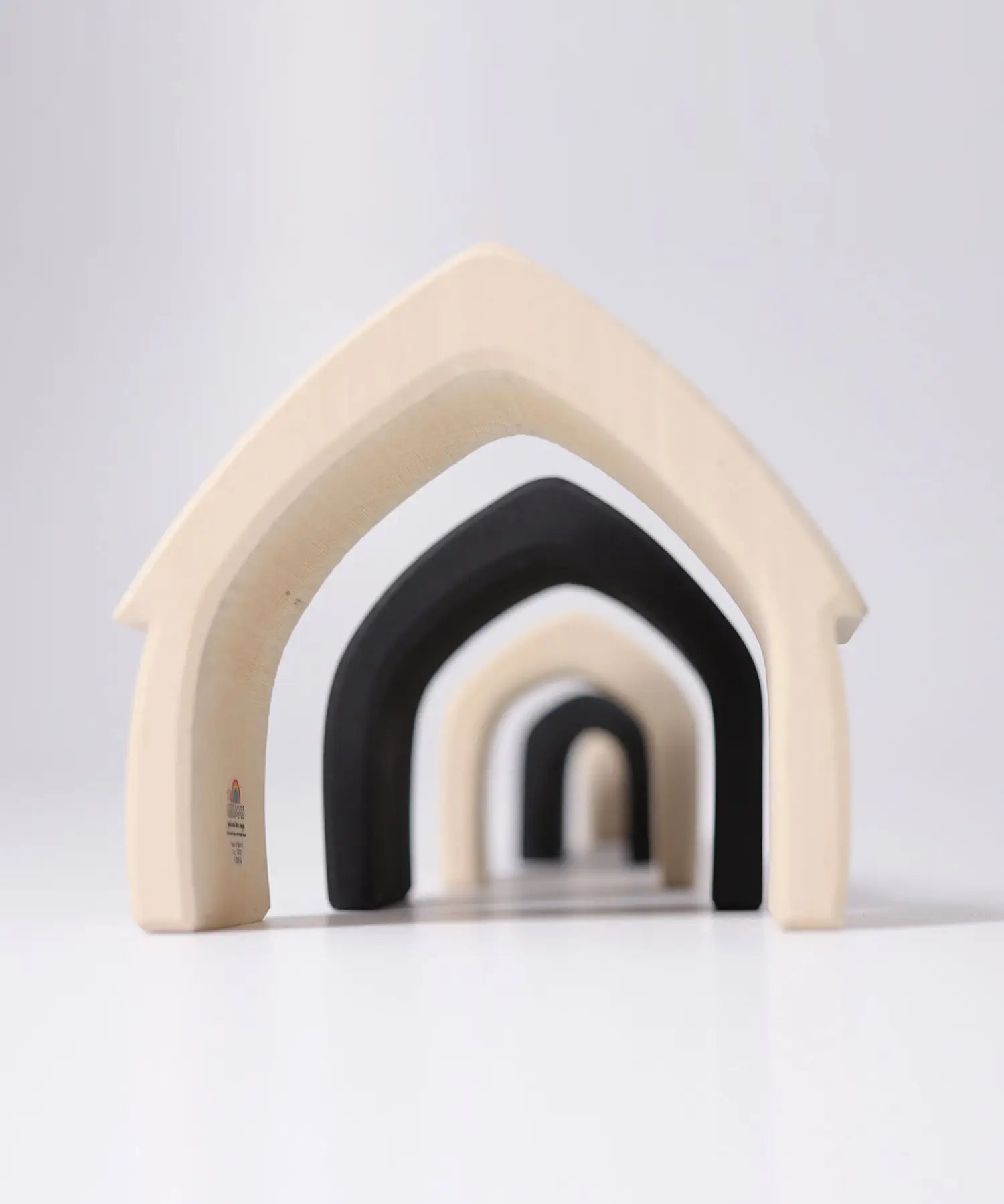 Loose Grimms handcrafted wooden monochrome house pieces lined up from large to small. 