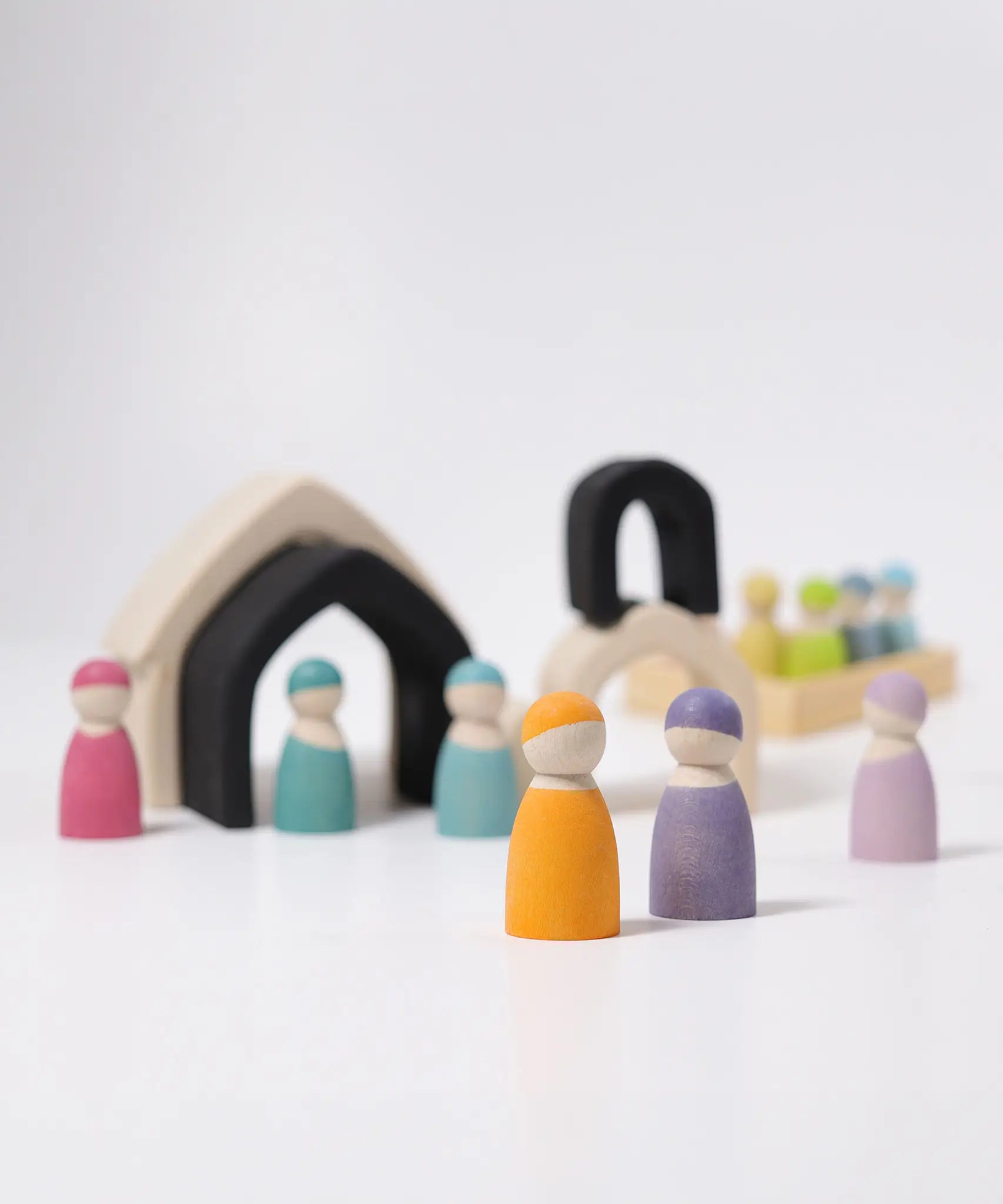 Loose Grimms monochrome house pieces next to pastel friends peg dolls in a play setup
