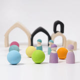 Loose Grimms wooden monochrome house pieces next to pastel balls and peg dolls in a play setup