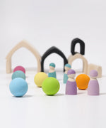 Loose Grimms wooden monochrome house pieces next to pastel balls and peg dolls in a play setup