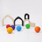 Loose Grimms wooden monochrome house pieces next to rainbow balls in a play setup