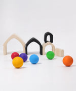 Loose Grimms wooden monochrome house pieces next to rainbow balls in a play setup