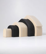 Individual wooden Grimms monochrome house pieces lined up from large to small. 