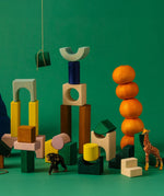 A playful stack made from the Grimm's movement hand carved pieces mixed with different animal figures and a stack of oranges 