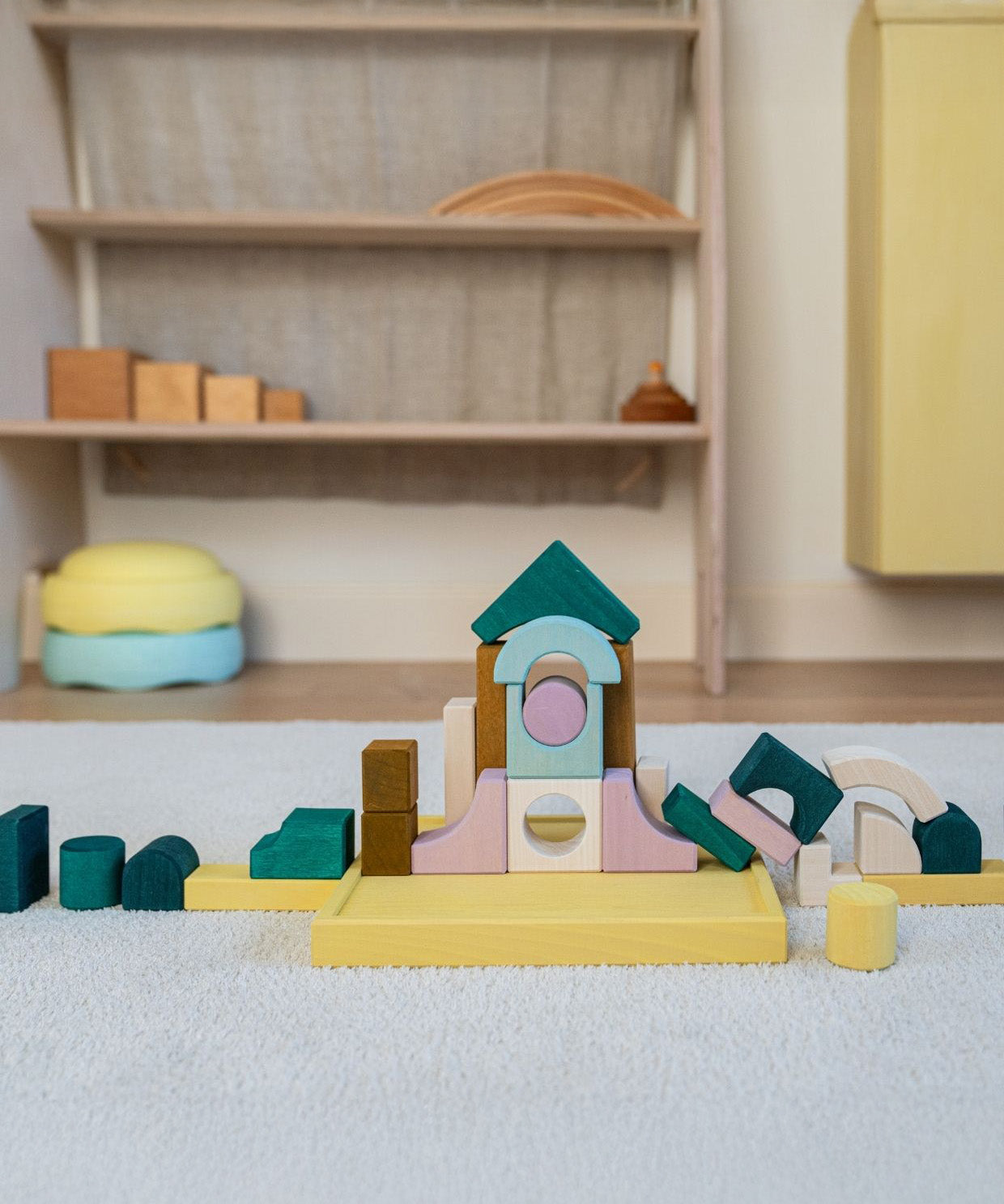 A simple construction made from Grimms movement building set on a fluffy rug in a playroom