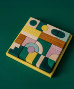 Grimm's wooden movement hand crafted pieces in a yellow square frame against a green background