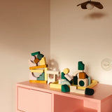 Loose pieces from the Grimms movement hand crafted building set on a pink drawer in a bedroom setting
