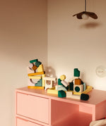 Loose pieces from the Grimms movement hand crafted building set on a pink drawer in a bedroom setting