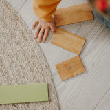 A chid hand next to loose Grimms wooden natural building boards showing scale