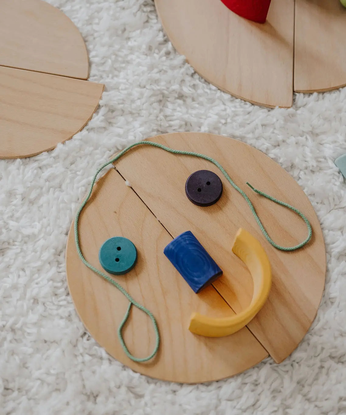 A flatlay showing loose Grimm's natural wooden semi circle pieces made into a face using other loose blocks