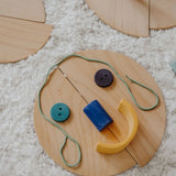 A flatlay showing loose Grimm's natural wooden semi circle pieces made into a face using other loose blocks