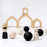 Loose Grimms handcrafted wooden natural house pieces made into a structure with monochrome peg dolls and balls in front.