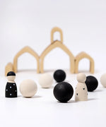 Loose Grimms handcrafted wooden natural house pieces made into a structure with monochrome peg dolls and balls in front.