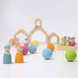 Loose Grimms handcrafted wooden natural house pieces made into a structure with pastel peg dolls and balls in front.