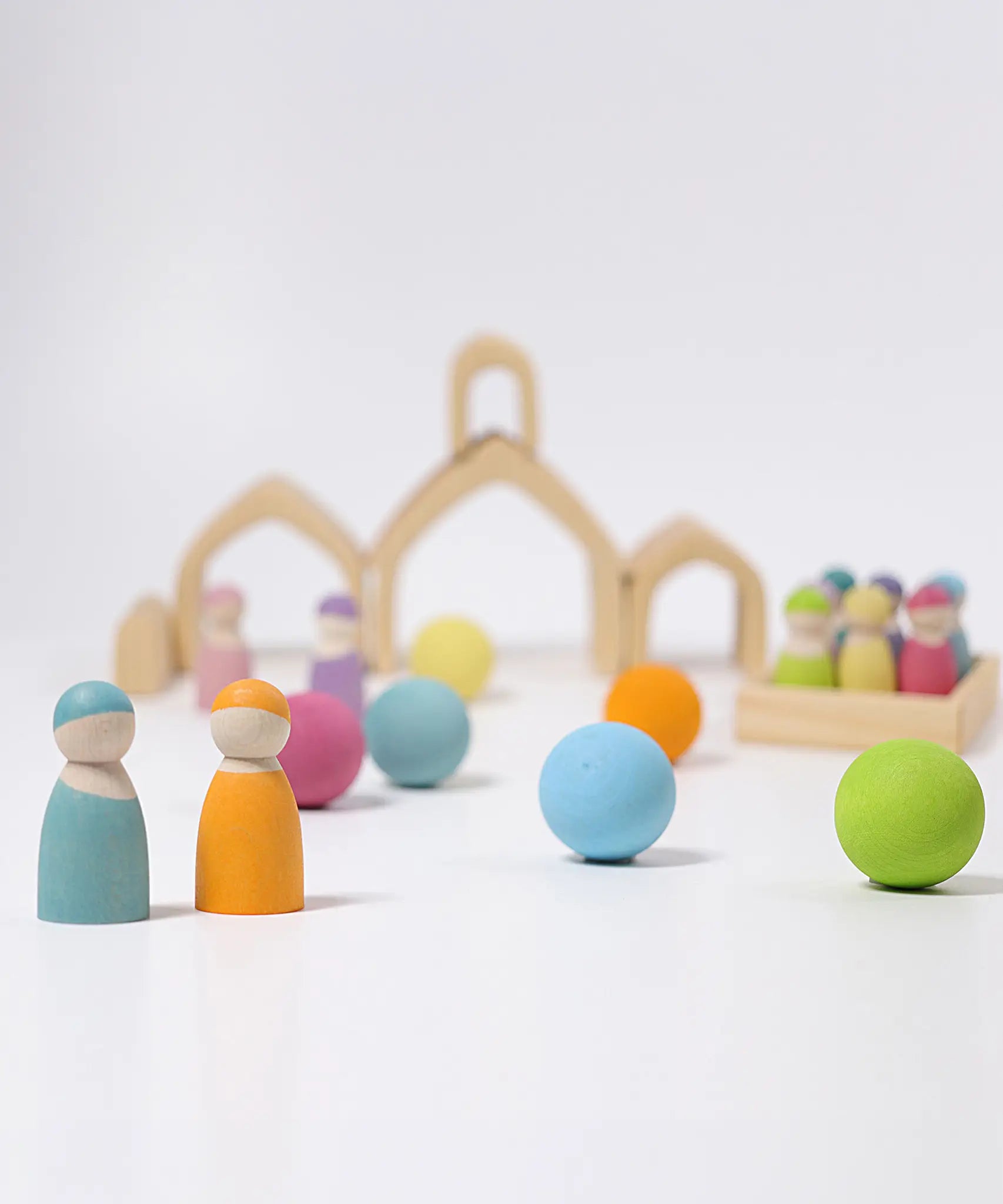Loose Grimms handcrafted wooden natural house pieces made into a structure with pastel peg dolls and balls in front.