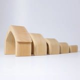 Individual wooden Grimms natural house pieces lined up from large to small. 
