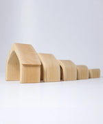 Individual wooden Grimms natural house pieces lined up from large to small. 