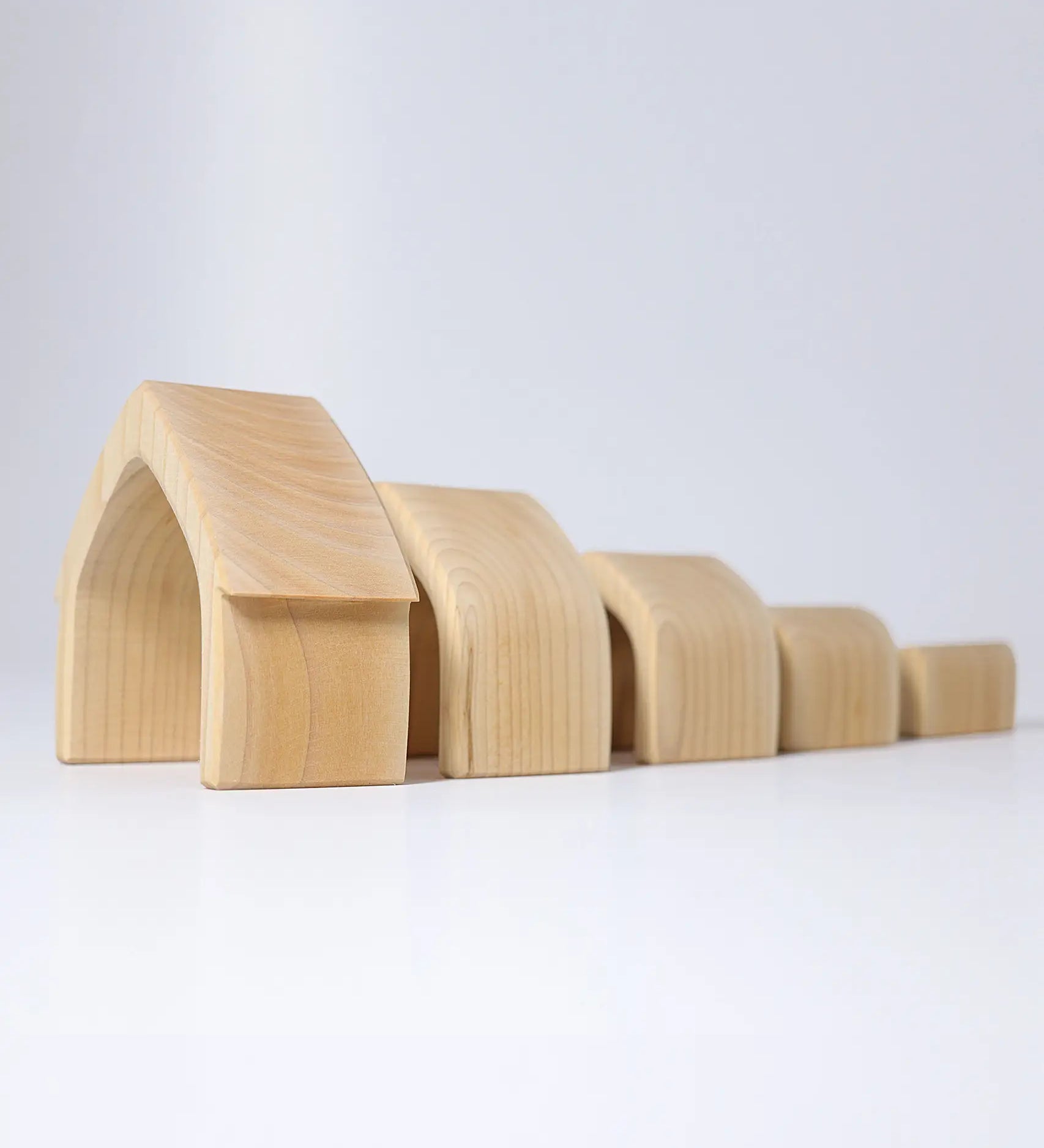 Individual wooden Grimms natural house pieces lined up from large to small. 
