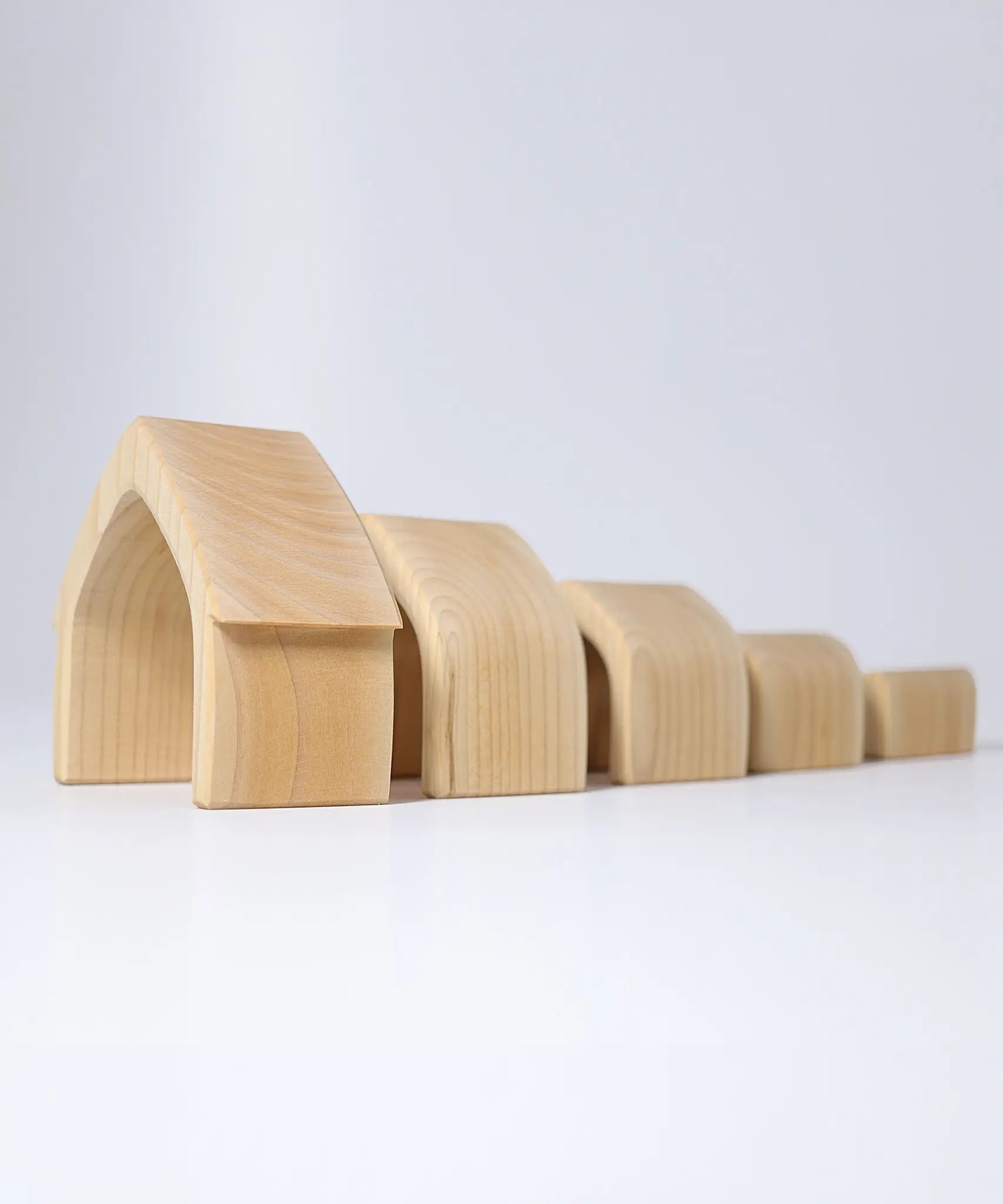 Individual wooden Grimms natural house pieces lined up from large to small. 