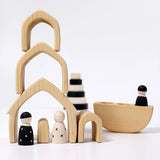 Individual wooden Grimms natural house pieces stacked on top of eachother with monochrome peg dolls underneath