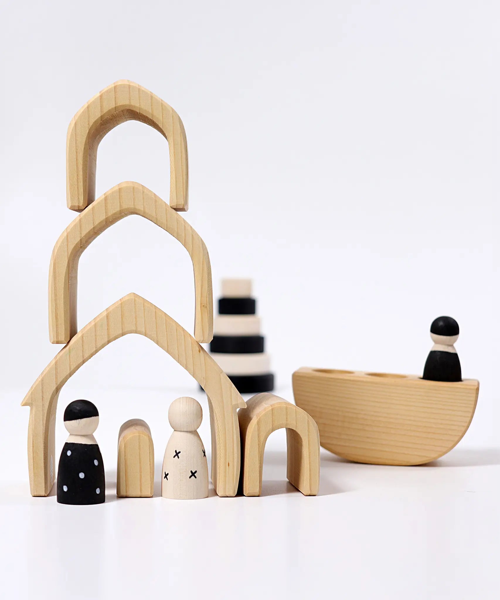 Individual wooden Grimms natural house pieces stacked on top of eachother with monochrome peg dolls underneath