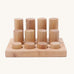 Different sized Grimms natural rollers on a wooden frame on a cream background.