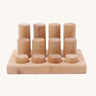 Different sized Grimms natural rollers on a wooden frame on a cream background.